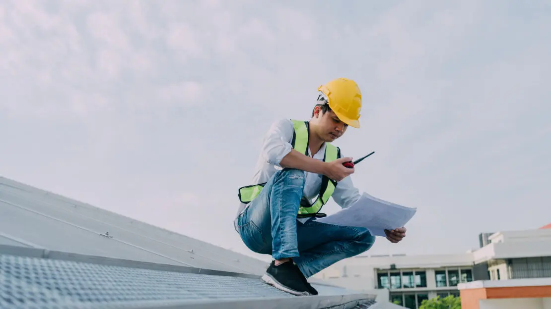 A roofer checking their roof maintenance checklist.